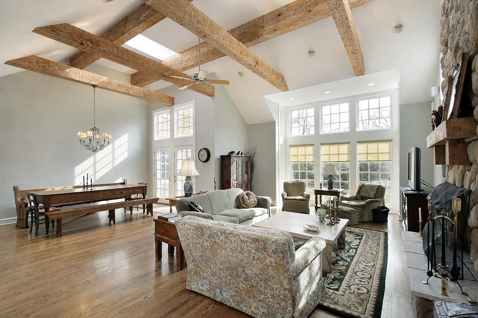Vaulted great room framed by a full box beam truss, with a stone fireplace and wide plank floors