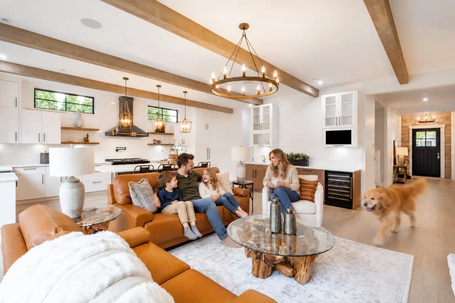 Family relaxing in an open living room and kitchen under wood box beams