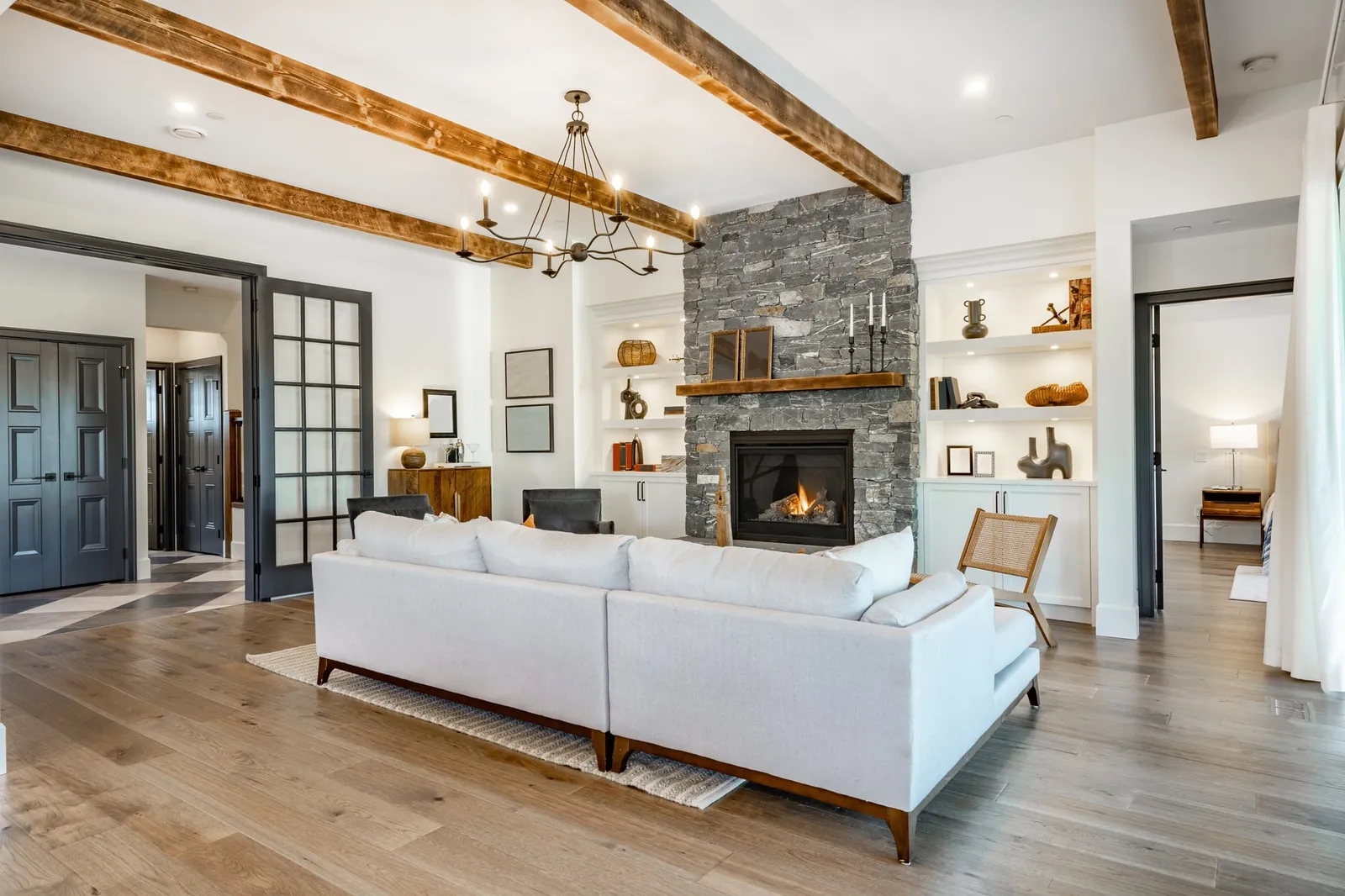Living room with wood box beams across the ceiling and a beam mantel above a stone fireplace
