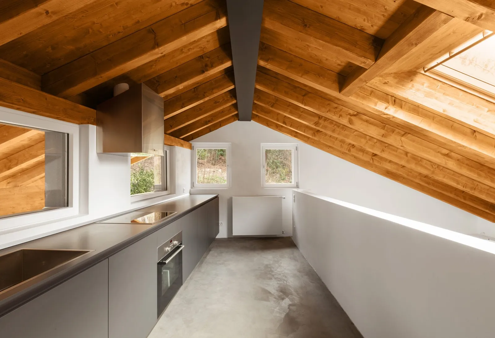 Loft kitchen under a vaulted plank ceiling carried on closely spaced wood beams