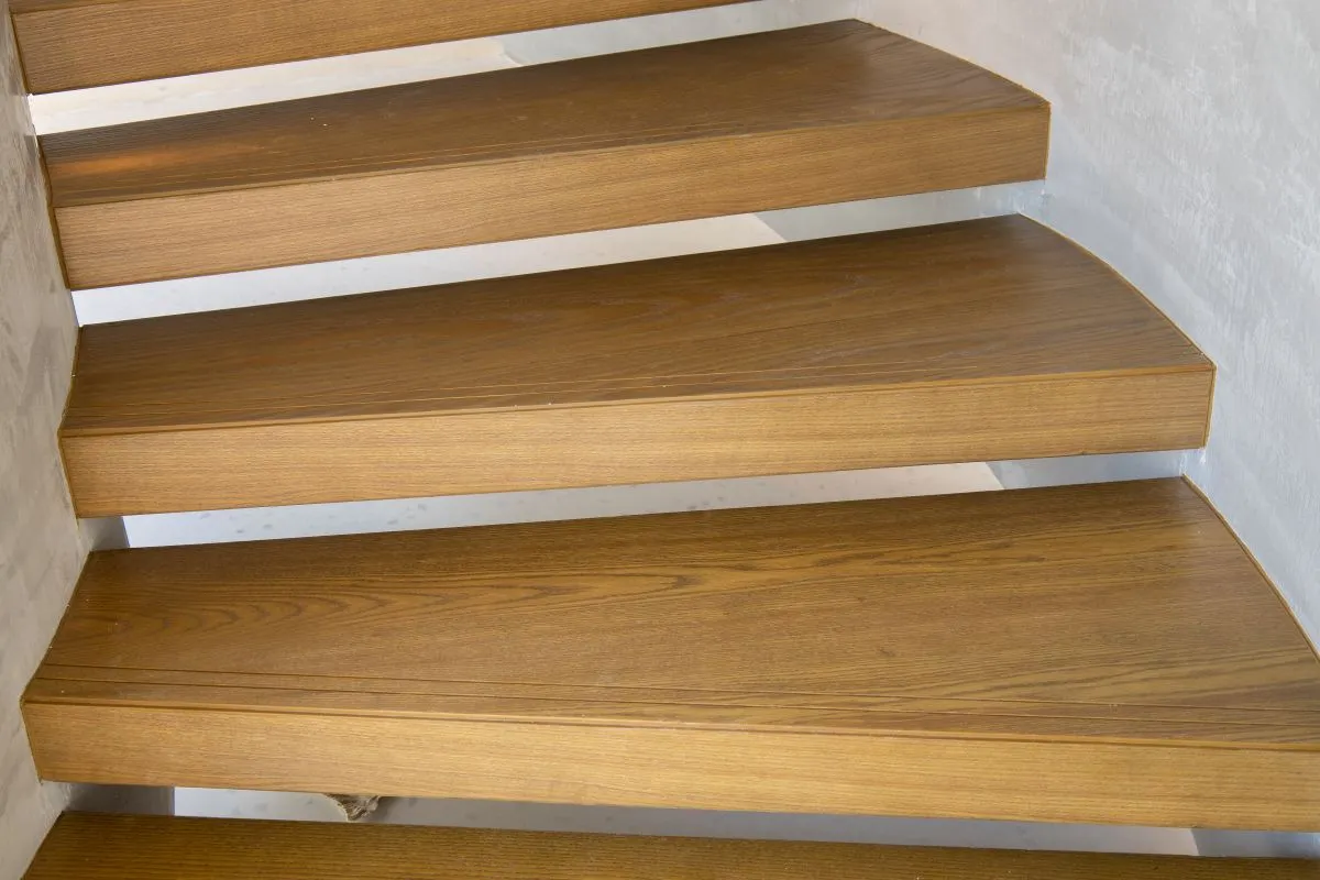Floating solid wood stair treads with mitered edges cantilevered from a plaster wall