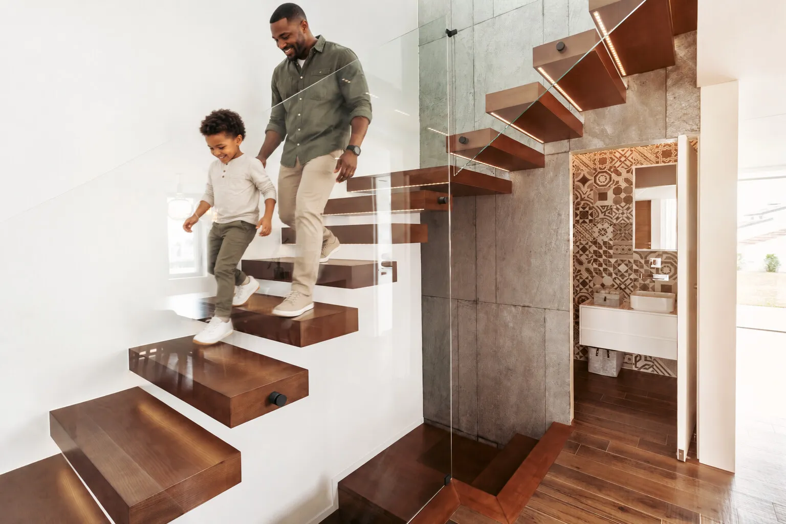 Floating solid wood stair treads beside a glass railing in a modern home