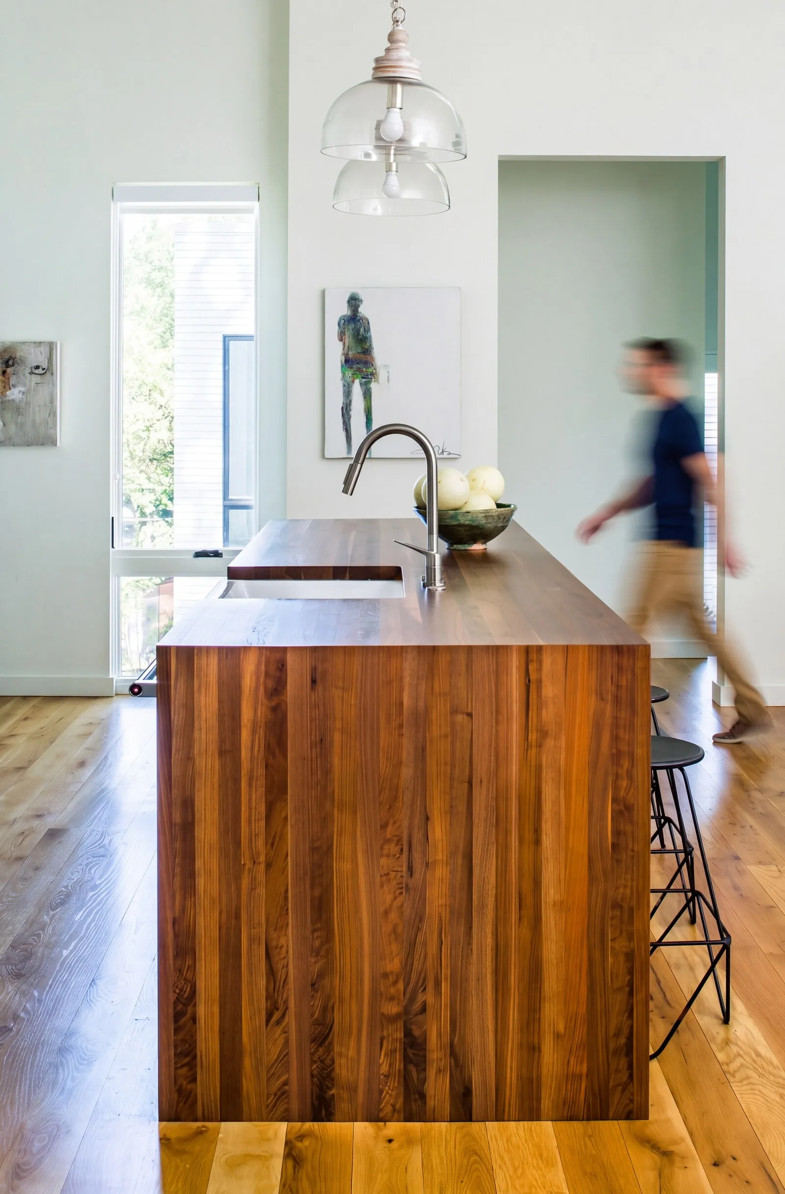 Walnut kitchen island with a waterfall edge and an integrated sink, on white oak floors